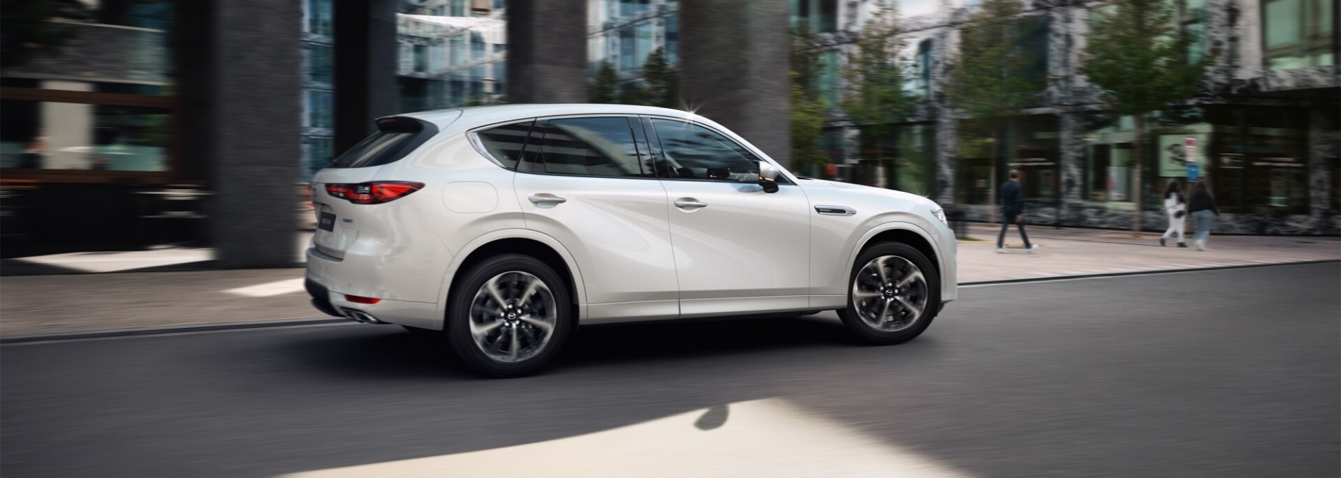 The all-new Mazda CX-60 Plug-In Hybrid SUV shown from the side driving down a city street.