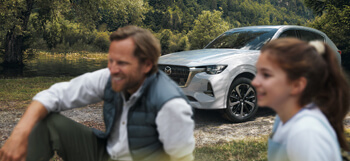 The all-new Mazda CX-60 Plug-In Hybrid SUV picture outside in nature with a man and a woman sitting nearby