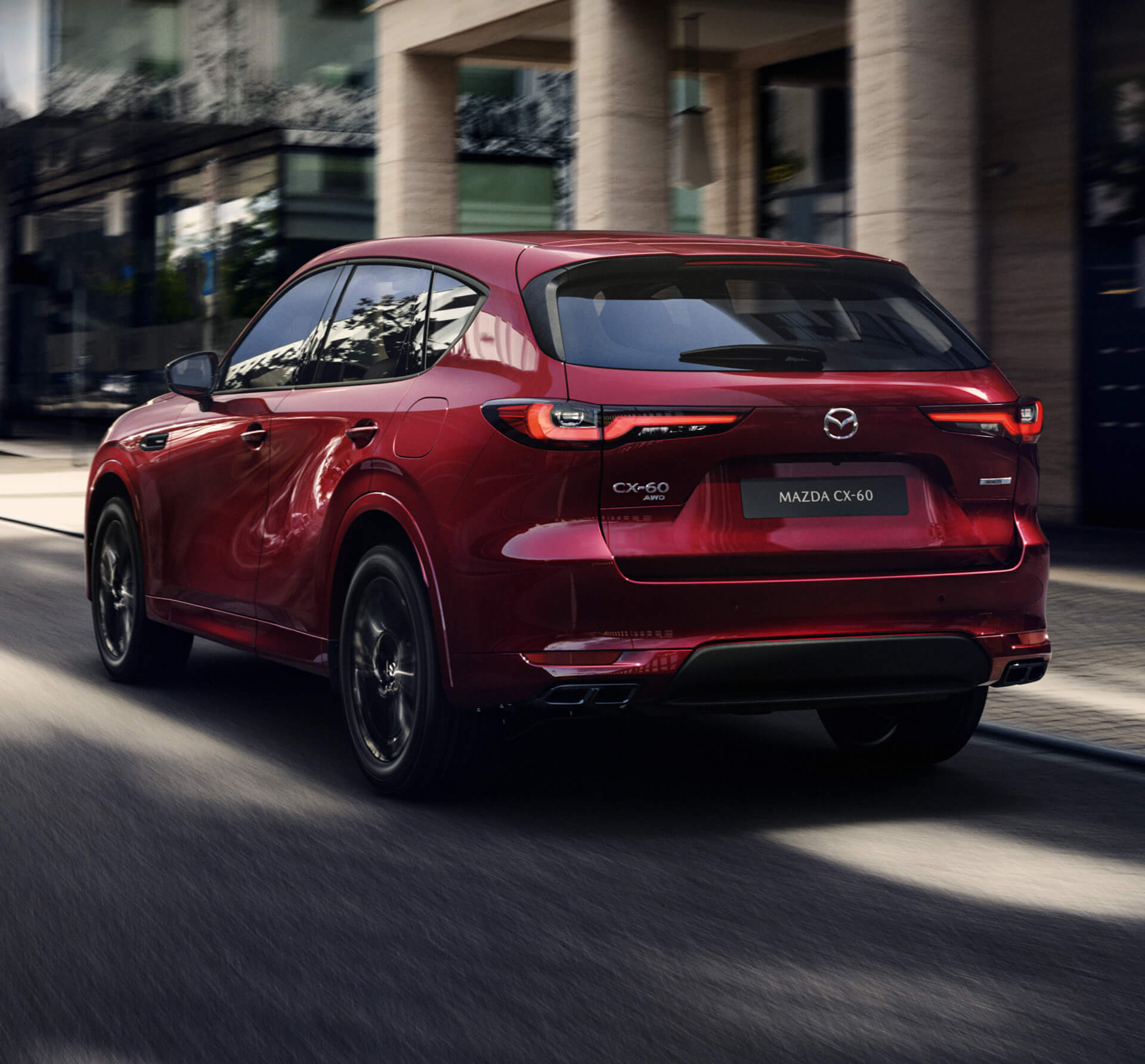 The all-new Mazda CX-60 Plug-In Hybrid SUV parked in front of a city building shown from the rear.